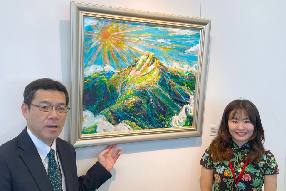 Two people standing beside a painting