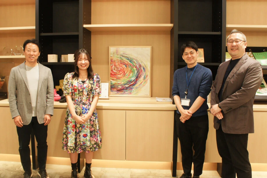 Four people beside a displayed painting
