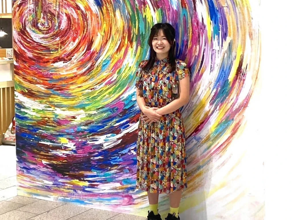 Artist standing beside a mural