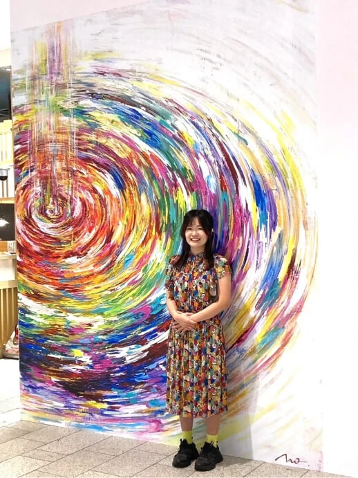 Artist standing beside a mall mural